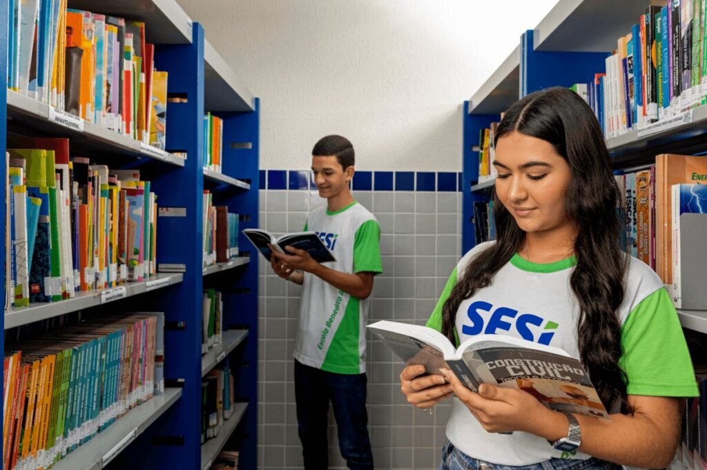 Estudantes pesquisando entre as estantes da biblioteca